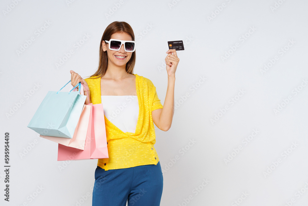 Happy young woman holding shopping bags and showing credit card isolated on white background. Happy young woman holding shopping bags and showing credit card isolated on white background.