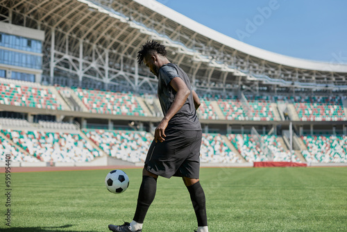 Professional football player in action at the stadium. The concept of sport, competition, movement, overcoming. The effect of the presence of the field. © Katsiaryna