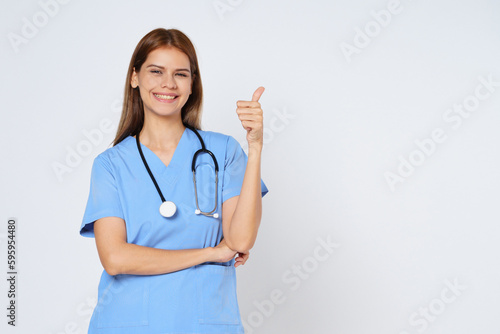 Portrait of smiling young woman doctor with stethoscope showing thumbs up isolate on white background.