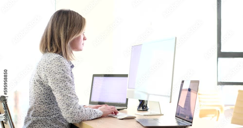 Woman manager works with data on computers and laptop at table. Multitasking and efficient work Woman manager works with data on computers and laptop at table. Multitasking and efficient work