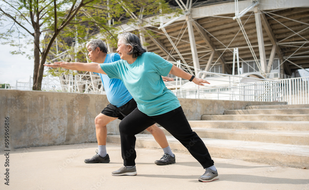 Asian senior couples wear sports outfit and warming up muscles  before exercise at outdoor in the morning. Happy elderly outdoor lifestyle concept, Full length of active happy elderly family couple