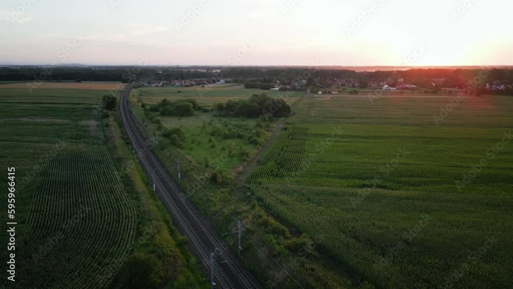 Aerial view of railway in countryside area at sunset. Railroad near agricultural fields Aerial view of railway in countryside area at sunset. Railroad near agricultural fields