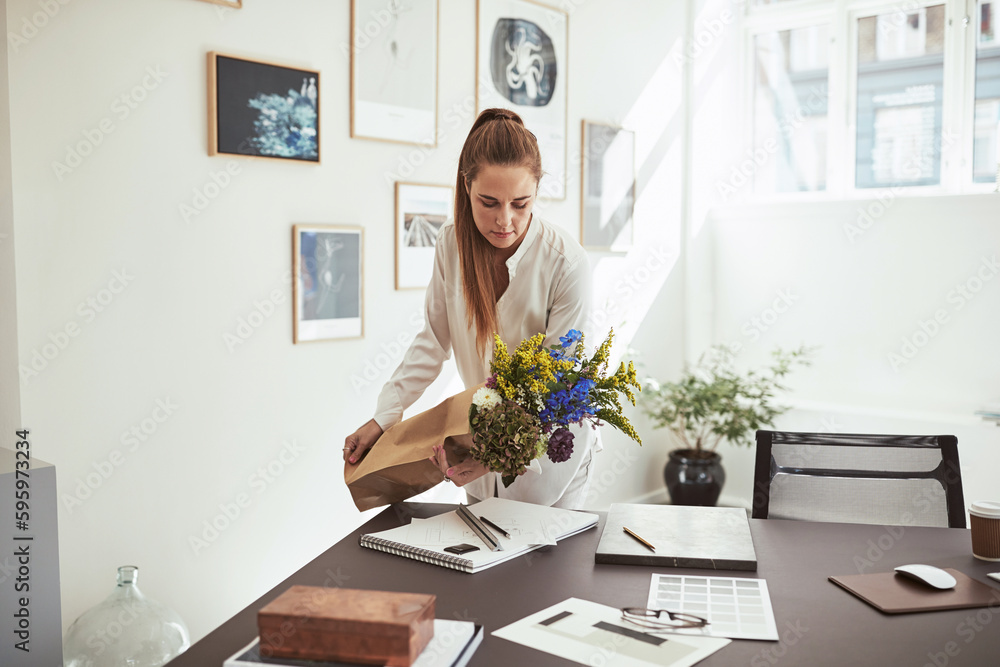 Smiling woman laying a flower bunch on her office desk Smiling woman laying a flower bunch on her office desk