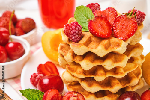 Healthy Breakfast set with Belgian waffles with strawberries, apricots, cherries, juice and a cup of black coffee and bitter chocolate on white stone table background