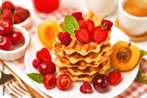 Healthy Breakfast set with Belgian waffles with strawberries, apricots, cherries, juice and a cup of black coffee and bitter chocolate on white stone table background