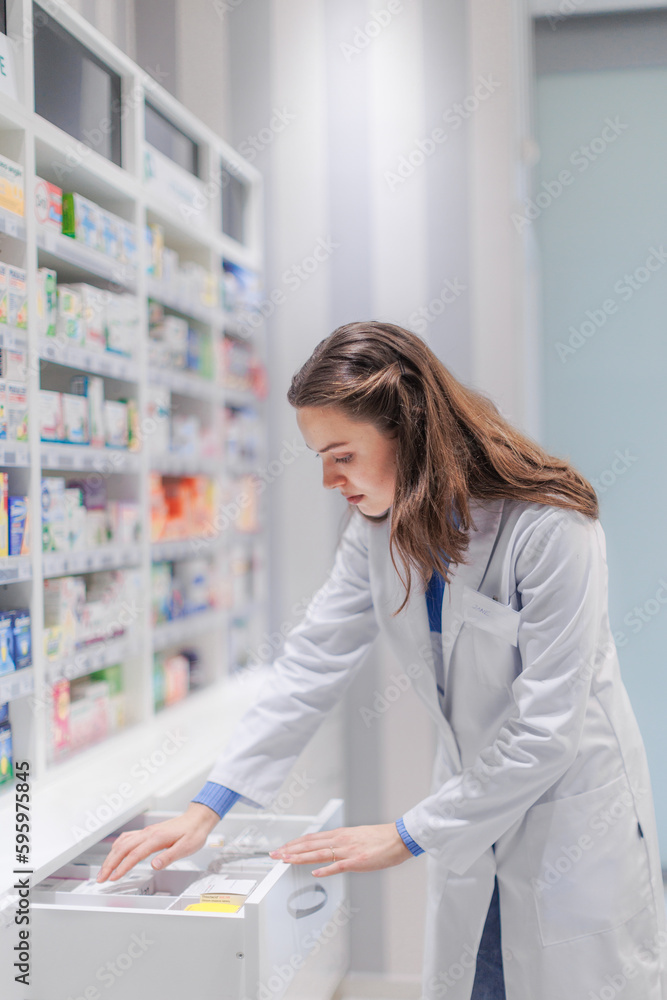 Young pharmacist checking medicine stock in pharmacy. Young pharmacist checking medicine stock in pharmacy.