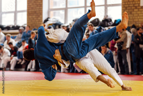 judoka in white kimono landing back his opponent in blue kimono, judo fight competition