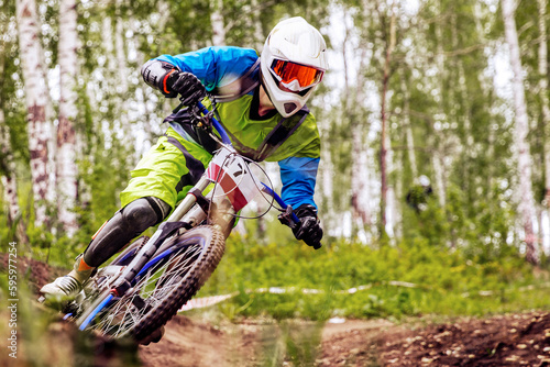 close-up racer athlete riding cornering turn downhill race, sports summer games in mountain bike