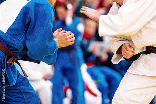 two judoists in blue and white kimono stand opposite each other, judo fight championship