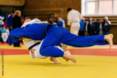 judoka in blue kimono landing back his opponent in white kimono, judo fight championship