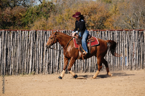 Western authentic lifestyle with cowgirl riding in arena during Texas autumn outdoors on ranch. © ccestep8