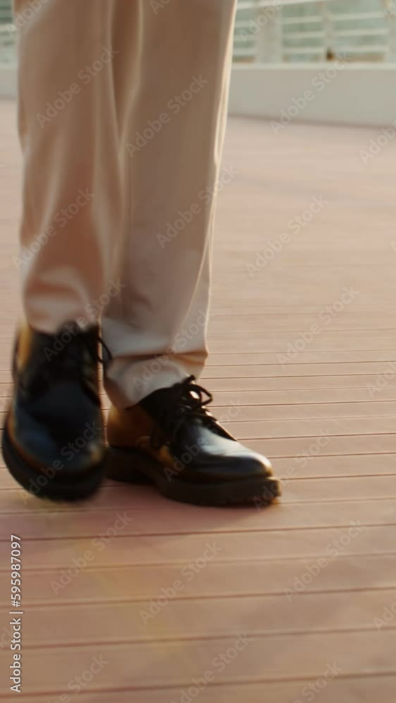 A man and a woman in business clothes are walking along the embankment. Legs close-up. A woman in high-heeled shoes A man and a woman in business clothes are walking along the embankment. Legs close-up. A woman in high-heeled shoes