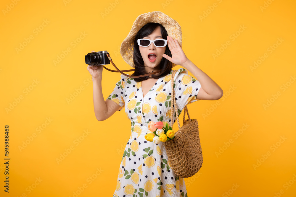 Studio portrait young pretty asian woman happy smile dressing springtime fashion with sunglasses, woven bag and holding tulip bouquet flower and camera against yellow studio background. Travel concept Studio portrait young pretty asian woman happy smile dressing springtime fashion with sunglasses, woven bag and holding tulip bouquet flower and camera against yellow studio background. Travel concept