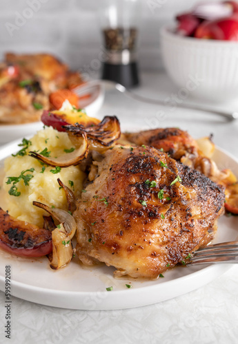 Baked chicken shanks with mashed potatoes, roasted, onions and apples on a plate