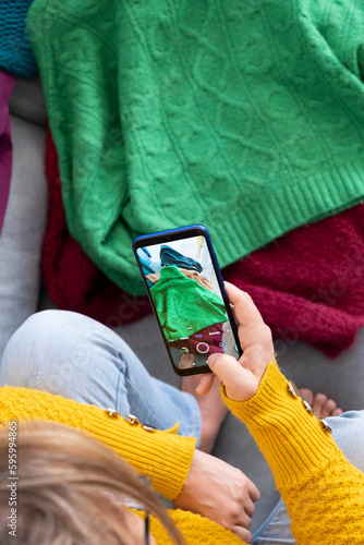 woman typing photo of clothes to sell in used clothing app, Top view from above, vertical
