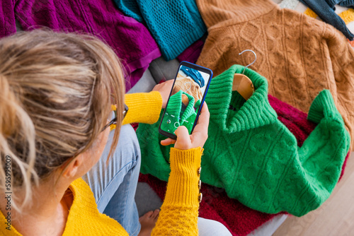 European young woman taking pictures of her clothes to sell them by second-hand app
