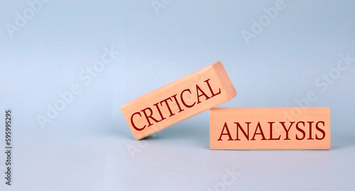 CRITICAL ANALYSIS text on the wooden block, blue background