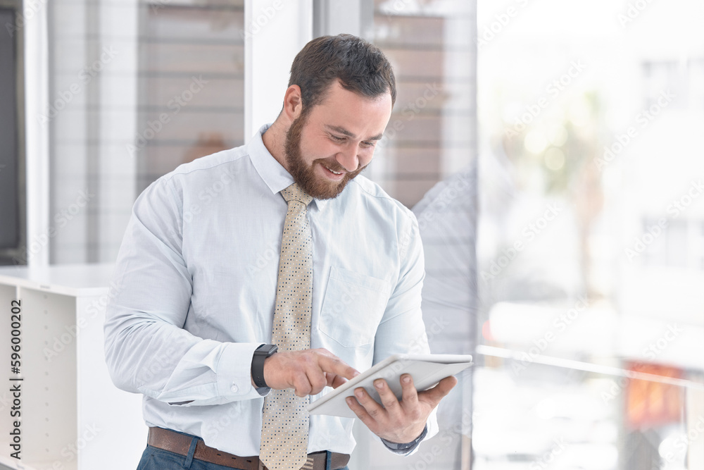 Fototapeta premium There are always simpler ways to work. a young businessman using a digital tablet while standing at a window in an office.
