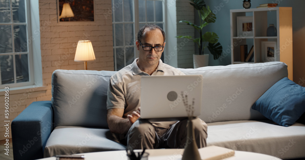 Successful male entrepreneur remotely working from home. Businessman using his laptop for surfing web and completing projects Successful male entrepreneur remotely working from home. Businessman using his laptop for surfing web and completing projects
