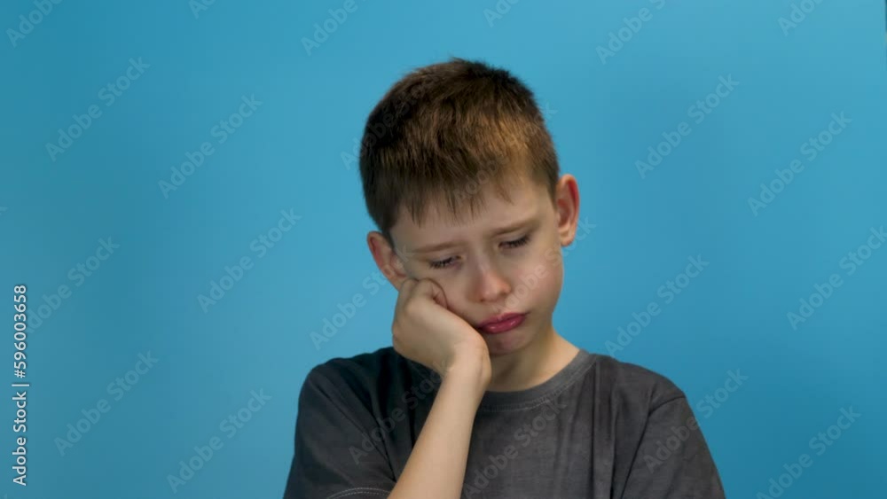 portrait of a tired caucasian boy 8-9 years old, bored against a blue background. Exhausted european schoolboy with a sad expression. The concept of fatigue and exhaustion portrait of a tired caucasian boy 8-9 years old, bored against a blue background. Exhausted european schoolboy with a sad expression. The concept of fatigue and exhaustion