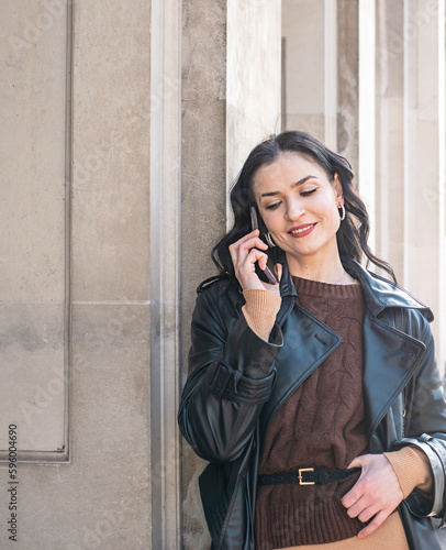 One woman modern mature caucasian female businesswoman with short hair using mobile phone making a call talk while walking on the stairs by building in day against concrete or stone wall copy space