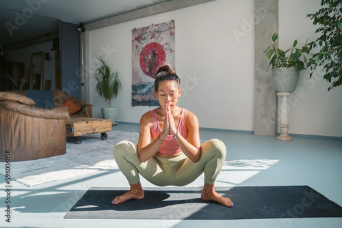 Flexible woman practicing meditation in Garland pose photo