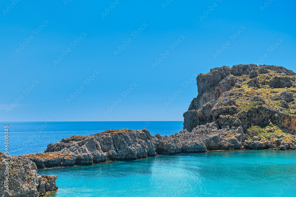 View from the beach of St. Paul's bay near the city of Lindos, clear blue sky and emerald sea, Rhodes island, Greek islands of the Dodecanese archipelago. Holidays and travel around the islands