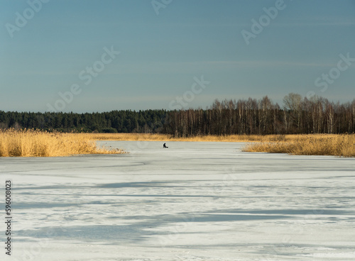 Fisherman on the lake in very cold winter day