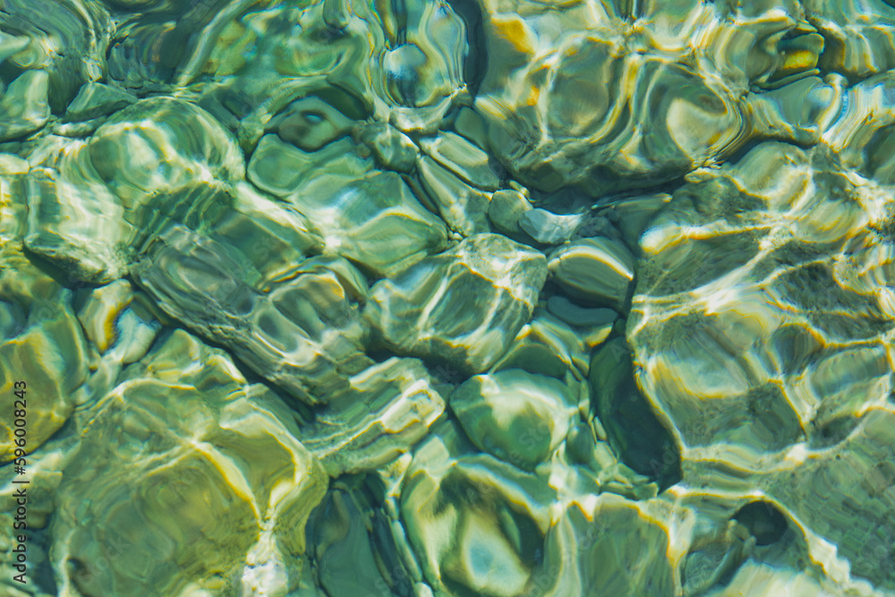 Blurred background of transparent clear water in the sea bay of the Aegean Sea glistens in the sun, idea for a background or postcard Blurred background of transparent clear water in the sea bay of the Aegean Sea glistens in the sun, idea for a background or postcard