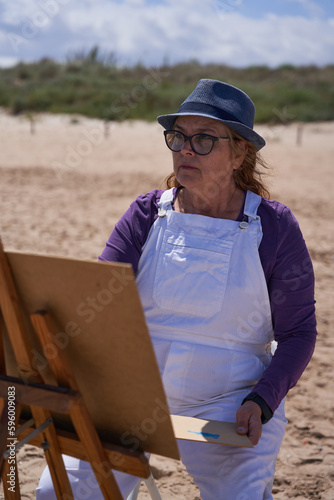 Lady painting a picture on the sand of the beach