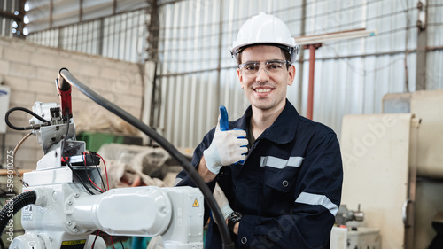 Industrial engineers are in charge of controlling the automated robot arms machine welding robots in industrial manufacturing factory.