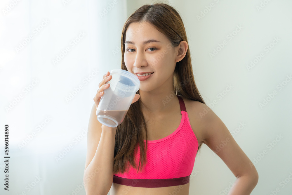 Diet meal replacement for weight loss, happy asian young woman, girl in sportswear, hand in holding protein shake bottle for drink supplement for muscle after workout at home. Healthy body care person Diet meal replacement for weight loss, happy asian young woman, girl in sportswear, hand in holding protein shake bottle for drink supplement for muscle after workout at home. Healthy body care person