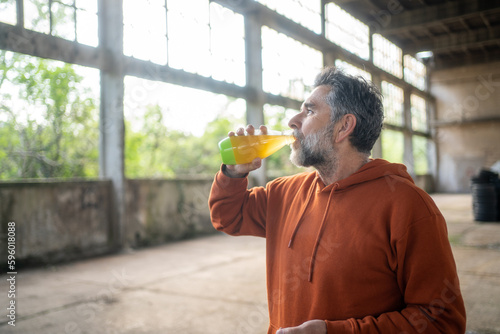 Active handsome mature man drinking fresh juice during break