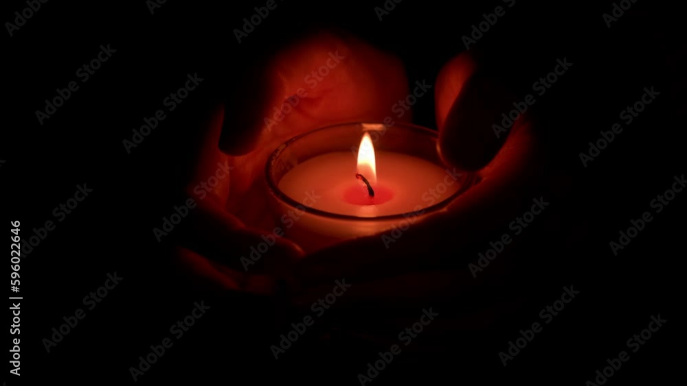A female hands holds a burning candle during a ritual, ceremony or prayer. Candke flikers bringing a feeling of peace and warmth. A female hands holds a burning candle during a ritual, ceremony or prayer. Candke flikers bringing a feeling of peace and warmth.