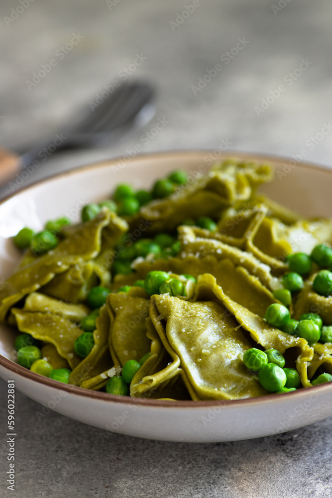 Homemade Italian tortellini with ricotta and spinach served with green pea sauce. A dish of classic Italian cuisine. Tortelloni di ricotta e spinaci. Close-up, selective focus