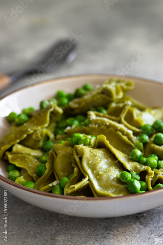 Homemade Italian tortellini with ricotta and spinach served with green pea sauce. A dish of classic Italian cuisine. Tortelloni di ricotta e spinaci. Close-up, selective focus