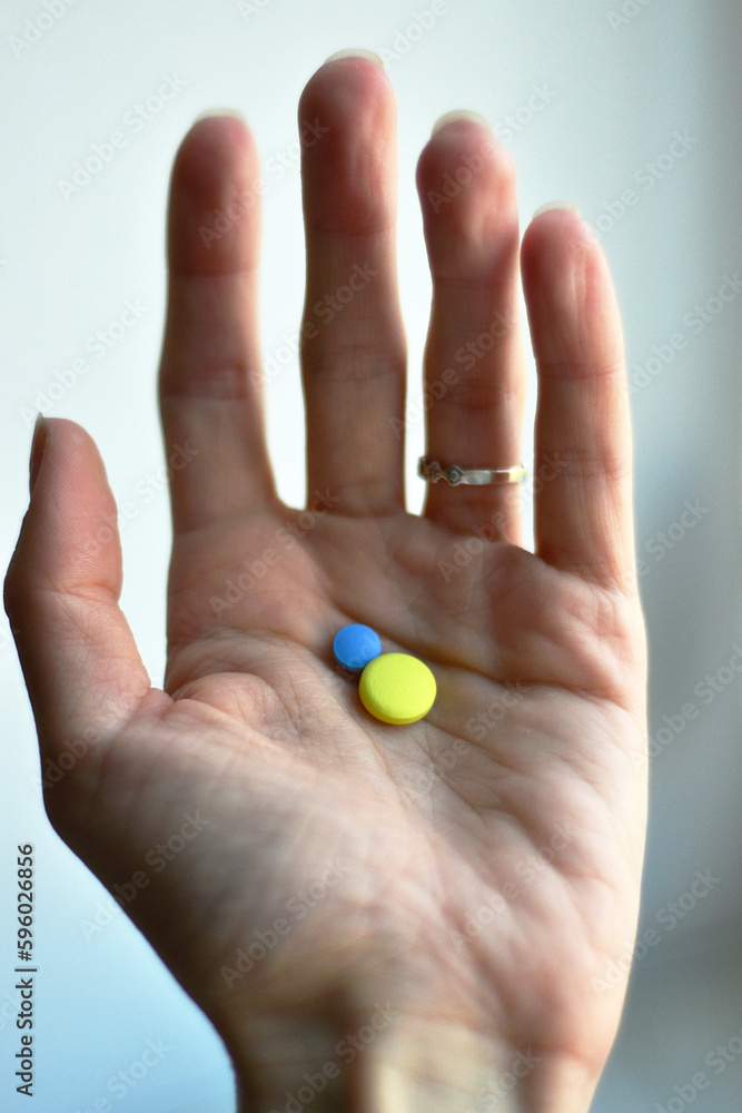 Hand holding yellow and blue pills. Hand holding yellow and blue pills.