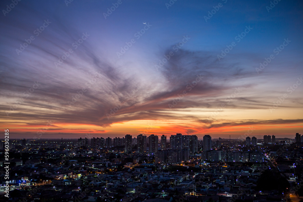 Sunset seen from above the building with orange and blue colored sky with the moon in the center and avenues and buildings highlighted. | Avenida Ayrton Senna em Natal, RN.