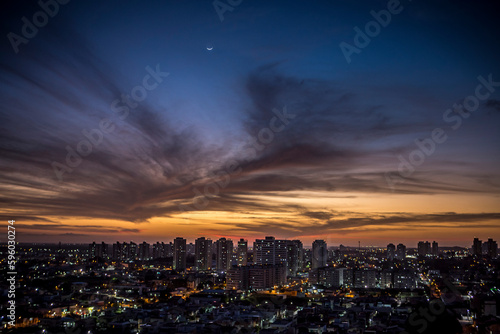 Sunset seen from above the building with orange and blue colored sky with the moon in the center and avenues and buildings highlighted. | Avenida Ayrton Senna em Natal, RN.