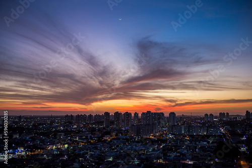 Sunset seen from above the building with orange and blue colored sky with the moon in the center and avenues and buildings highlighted.   Avenida Ayrton Senna em Natal, RN. © Laíne Paiva