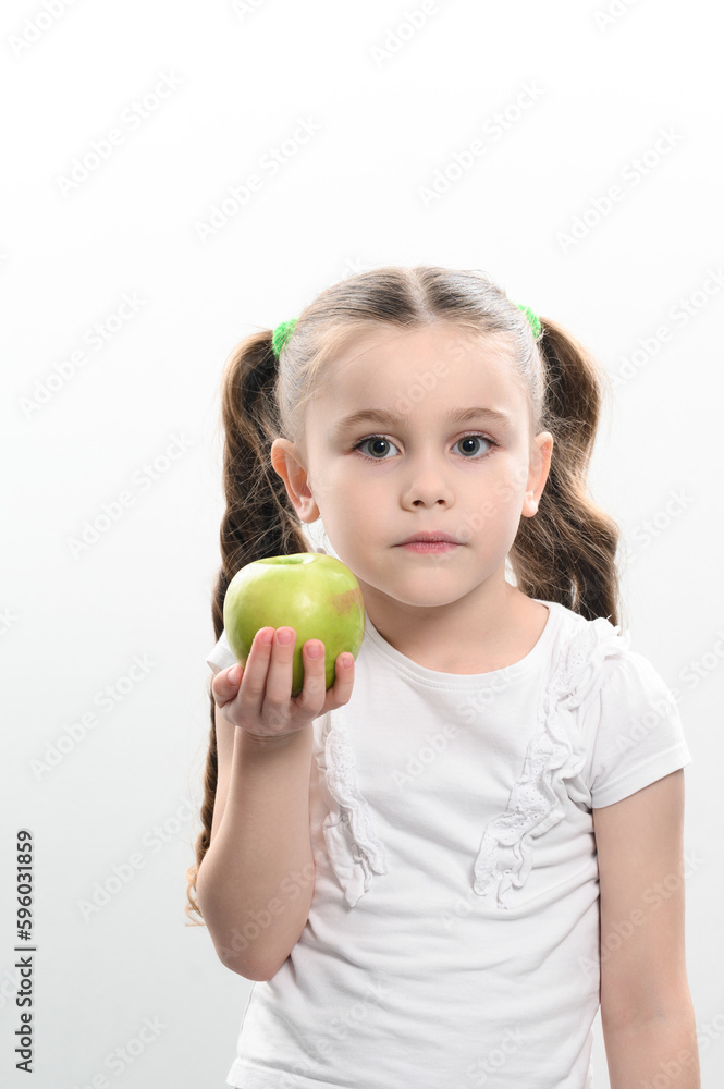 A little girl holds a green apple in her hands A little girl holds a green apple in her hands