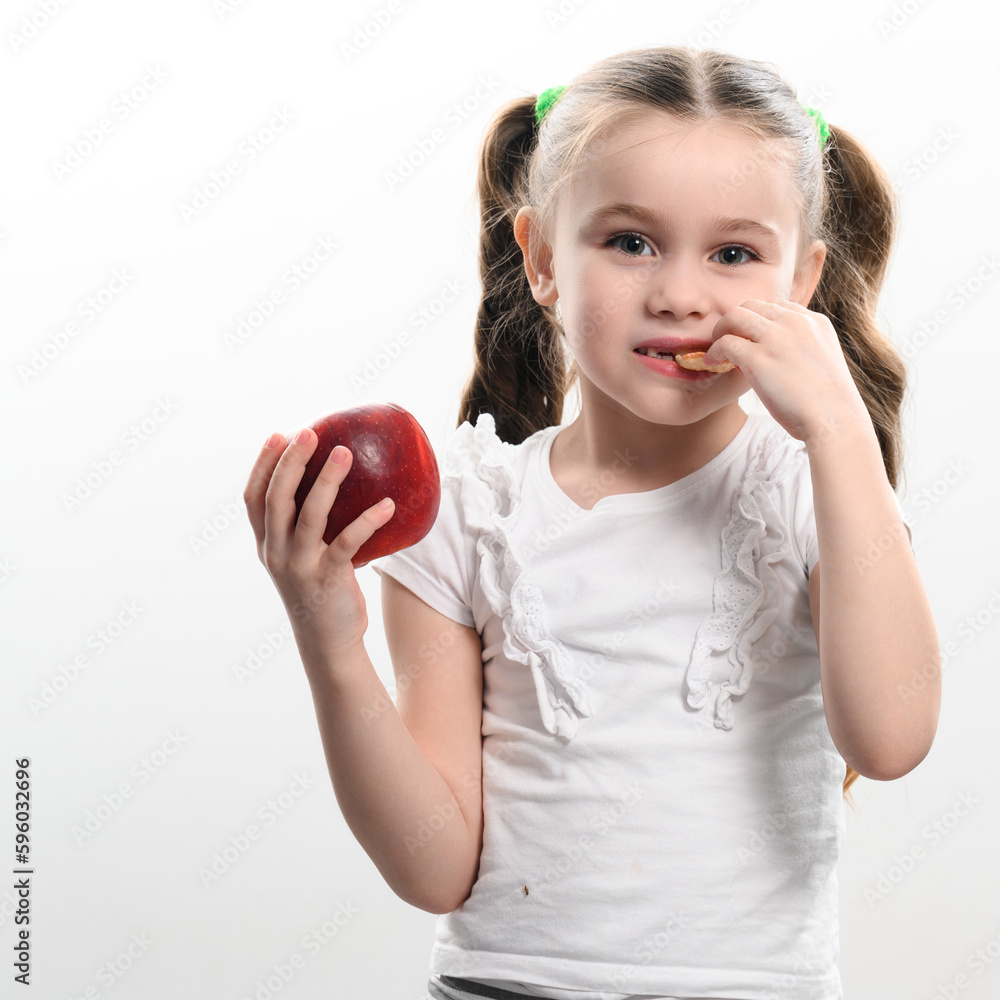 A little girl is holding one apple and chips on a white background.