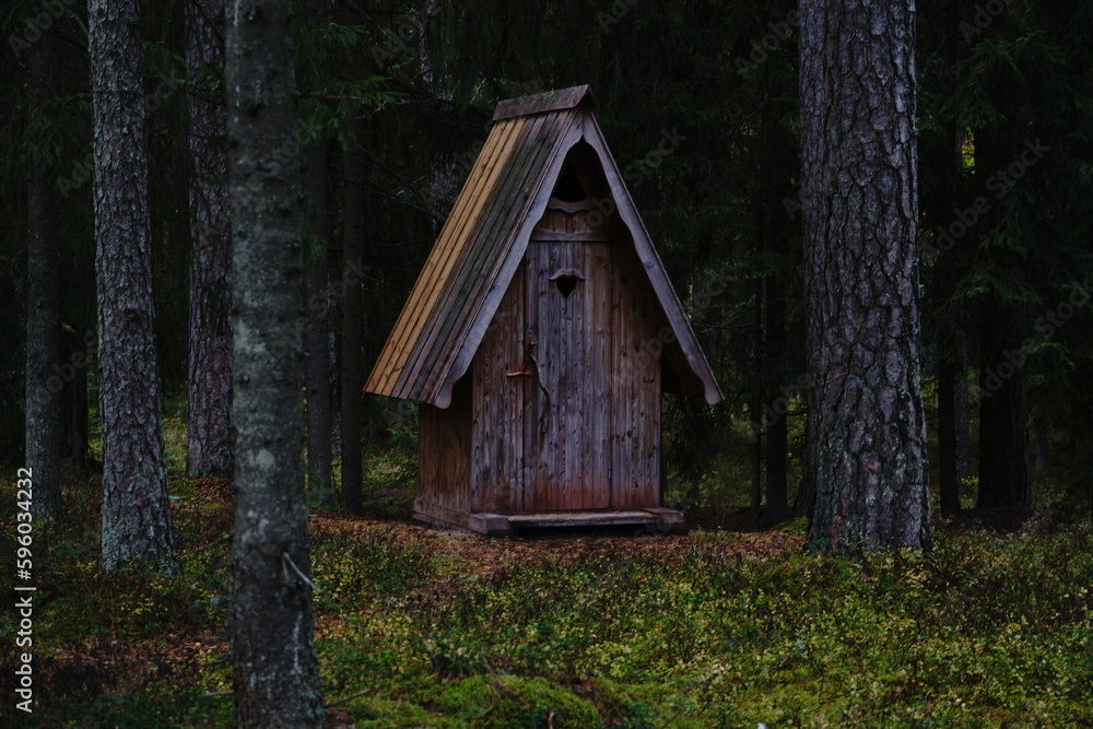 small wooden outdoor toilet in forest behind trees with heart shaped hole small wooden outdoor toilet in forest behind trees with heart shaped hole