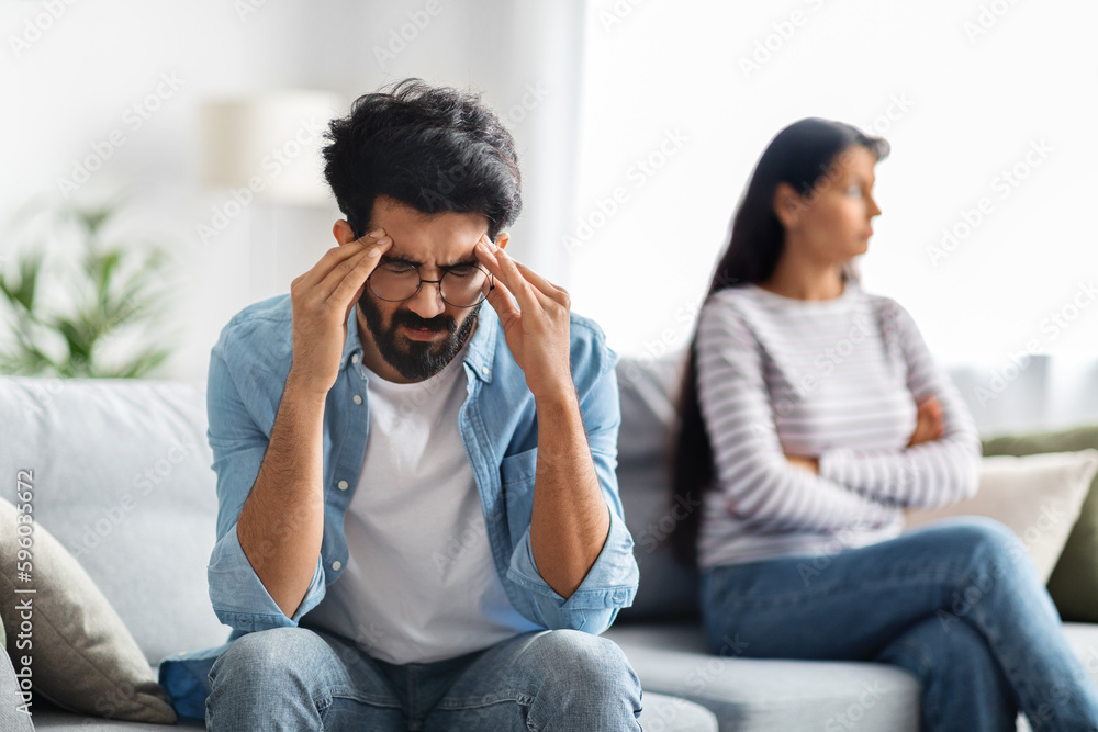 Fototapeta premium Frustrated indian man touching his head, fighting with wife