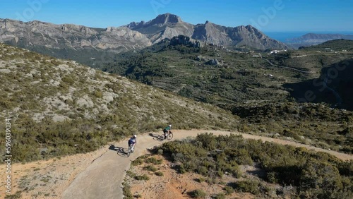 Gravel Cycling on Spain's Costa Blanca: Aerial Drone Footage Captures Cyclists Descending a Serpentine Mountain Road. Beautiful view on Bernia mountains. Aerial drone footage  photo