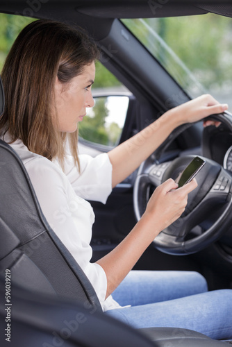 woman texting on smartphone while driving a car © auremar