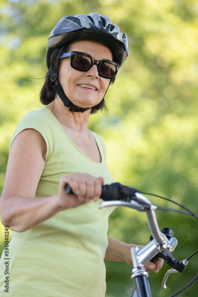 Naklejka premium senior female cyclist wearing helmet and sunglasses