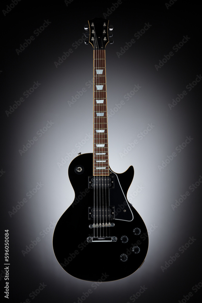 Black guitar isolated on dark grey eclipse background