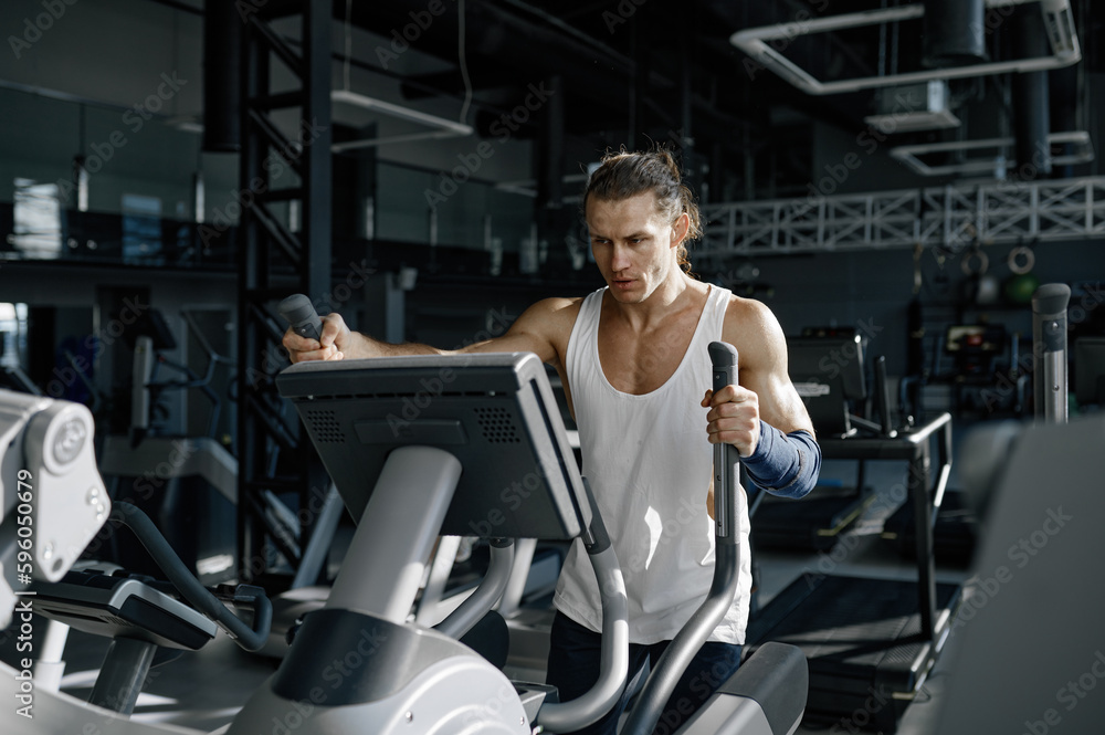 Sweaty sportsman doing cardio exercise on orbitrack training apparatus Sweaty sportsman doing cardio exercise on orbitrack training apparatus