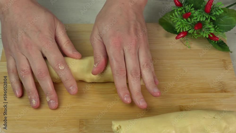 A man rolls out the dough with his hands on a cutting board for making shortcrust pastry. Cooking pastry or dessert A man rolls out the dough with his hands on a cutting board for making shortcrust pastry. Cooking pastry or dessert